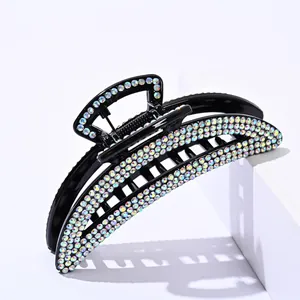 Close-up of elegant black hair claw clip with shimmering rhinestones on white stand