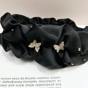 Détail d'un serre-tête en satin noir plissé orné de papillons incrustés de cristaux