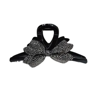 Dettaglio di un fermaglio per capelli nero con fiocco di strass su uno sfondo bianco puro