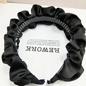 Détail des dents antidérapantes et des plis en satin sur le serre-tête noir chic