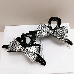 Elegant bow-shaped hair claw clips with sparkling rhinestones in a minimalist black finish