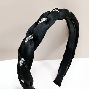 Dettaglio di un cerchietto in raso intrecciato nero con strass lucidi e dentini antiscivolo