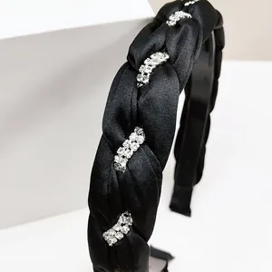Dettaglio del cerchietto in raso intrecciato nero con decorazioni di strass scintillanti