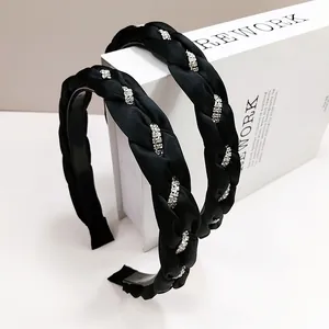 Cerchietti intrecciati in raso nero con strass argentati su un supporto decorativo bianco