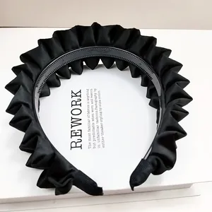 Détail d'un serre-tête en satin plissé noir avec dents antidérapantes et tissu texturé
