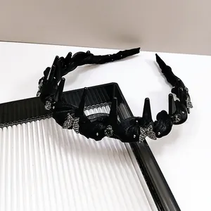 Détail d'un serre-tête tressé noir avec papillons en strass et pointes de style gothique