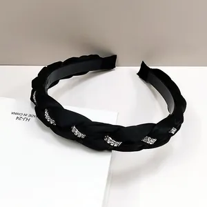 Dettaglio di un cerchietto in raso nero intrecciato decorato con strass argentati luccicanti