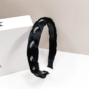 Dettaglio del cerchietto a treccia in raso nero con strass argentati su espositore bianco