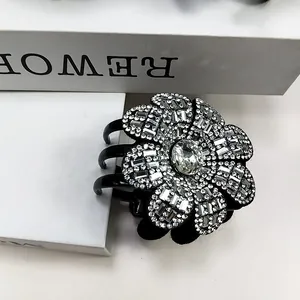 Vue détaillée d'une grande pince à cheveux fleur noire ornée de strass brillants