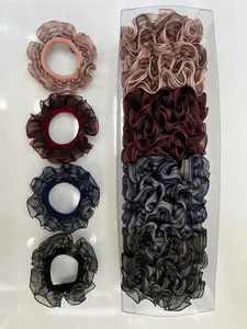 Detalle de coleteros de organza plisada en rosa, rojo, azul y negro en estuche