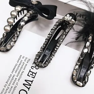 Close-up of black satin bow hair clip with luxury rhinestones and pearl accents