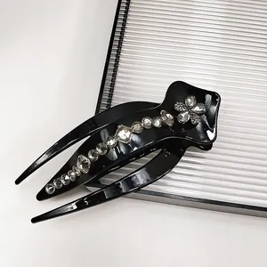 Detailed close-up of glossy black hair claw clip with sparkling rhinestone floral pattern