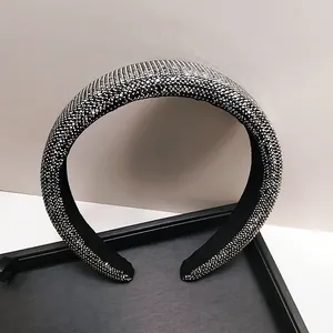 Detail van een gewatteerde haarband met zilveren strass-steentjes op zwart fluweel