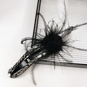 Detailed view of luxury black feather hair clip with sparkling rhinestones and glossy finish
