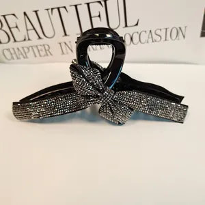 Close-up of a black hair claw clip featuring a sparkling rhinestone bow design