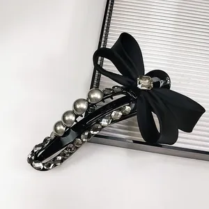 Macro shot of luxury black bow hair claw with grey pearls and sparkling rhinestones