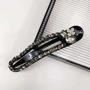 Detail of black bow hair clip with gray rhinestones, transparent gems, and a white flower