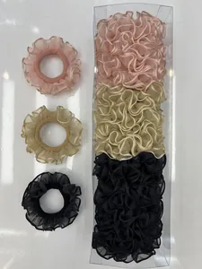 Detalle de coleteros de malla plisada en rosa, beige y negro con caja de regalo
