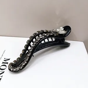 Detail of black resin banana clip with sparkling rhinestones and white floral accent