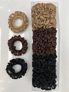 Detalle de coleteros plisados de satén en champán, marrón y negro en caja de regalo