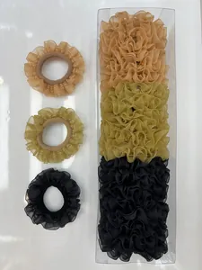 Detalle de coleteros de organza con volantes en caramelo, verde y negro en caja de regalo