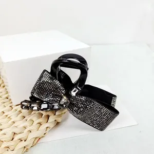 Elegant black hair claw clip featuring a sparkling rhinestone bow and grey crystals