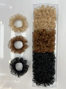 Tres coleteros de organza en beige marrón y negro con una caja de plástico clara