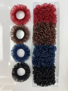 Detalle de coleteros rizados en rojo, marrón, azul y negro con caja de regalo transparente