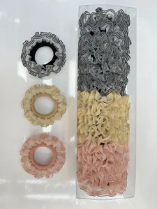 Primer plano de coleteros de organza plisados en negro, amarillo y rosa con caja de venta