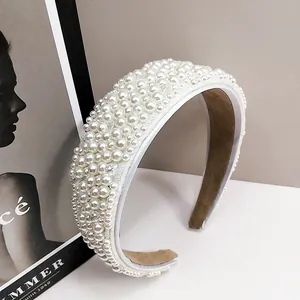 Detalle de una diadema ancha blanca decorada con bordado denso de perlas brillantes