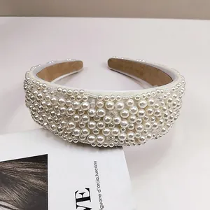Detalle de perlas blancas cosidas a mano en una diadema ancha de satén de lujo