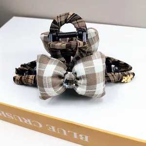 Detail of plaid bow hair claw clip with crystal center and golden bear charm pendant
