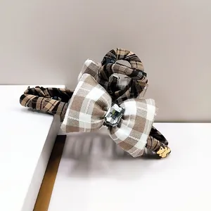 Detail of checkered fabric hair claw with crystal bow and golden bear pendant accessory
