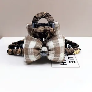 Detail view of plaid bow hair claw clip with large clear gemstone and gold bear charm
