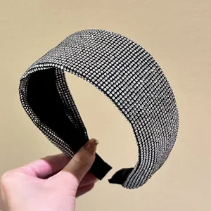 Close-up of a wide sparkling headband with full crystal rhinestones and black fabric lining