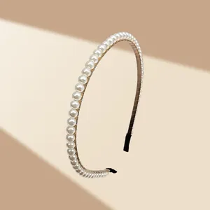 Detalle macro de perlas blancas en diadema de metal dorado con protectores finales negros