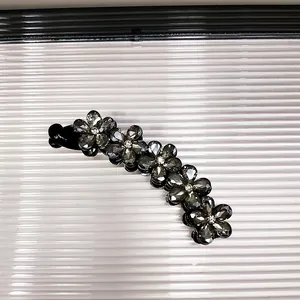 Dettaglio della clip a banana con fiori di cristallo grigio su sfondo a righe