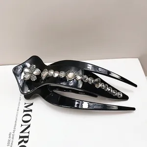 Close-up of black glossy hair clip with shimmering floral rhinestone patterns