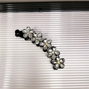 Dettaglio di un fermaglio a banana coreano con cinque decorazioni floreali in cristallo