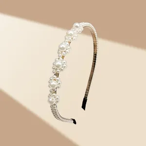 Primer plano de diadema artesanal con flores de perlas blancas y estructura dorada