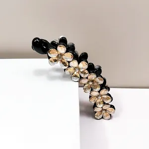 Dettaglio di fiori in cristallo champagne su un elegante fermaglio per capelli nero