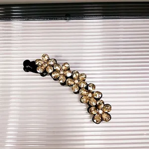 Dettaglio di cinque fiori di cristallo su un fermaglio a banana nero da donna
