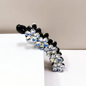 Dettaglio macro del fermaglio a banana nero con fiori di strass colorati scintillanti