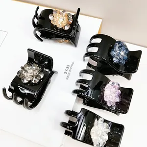 Close-up of five crystal flower hair claws in champagne, blue, purple, and grey colors