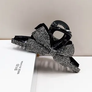 Dettaglio della pinza per capelli a fiocco nero con strass luccicanti e finitura lucida