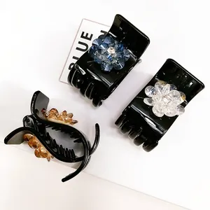 Three crystal flower hair claw clips in blue, clear, and amber on a clean background