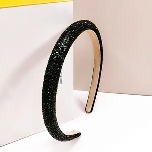 Macro detail of luxury black rhinestone headband with sparkling pavé crystals and thick padding
