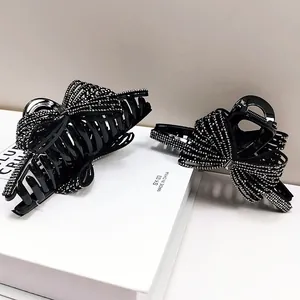 Dettaglio di due mollette per capelli nere con strass argentati su una scatola regalo bianca