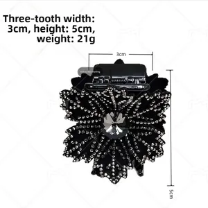 Detail view of a black 3-prong hair clip with sparkling rhinestone flower design