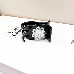 Detail of elegant black hair claw with a white crystal flower and sparkling centerpiece